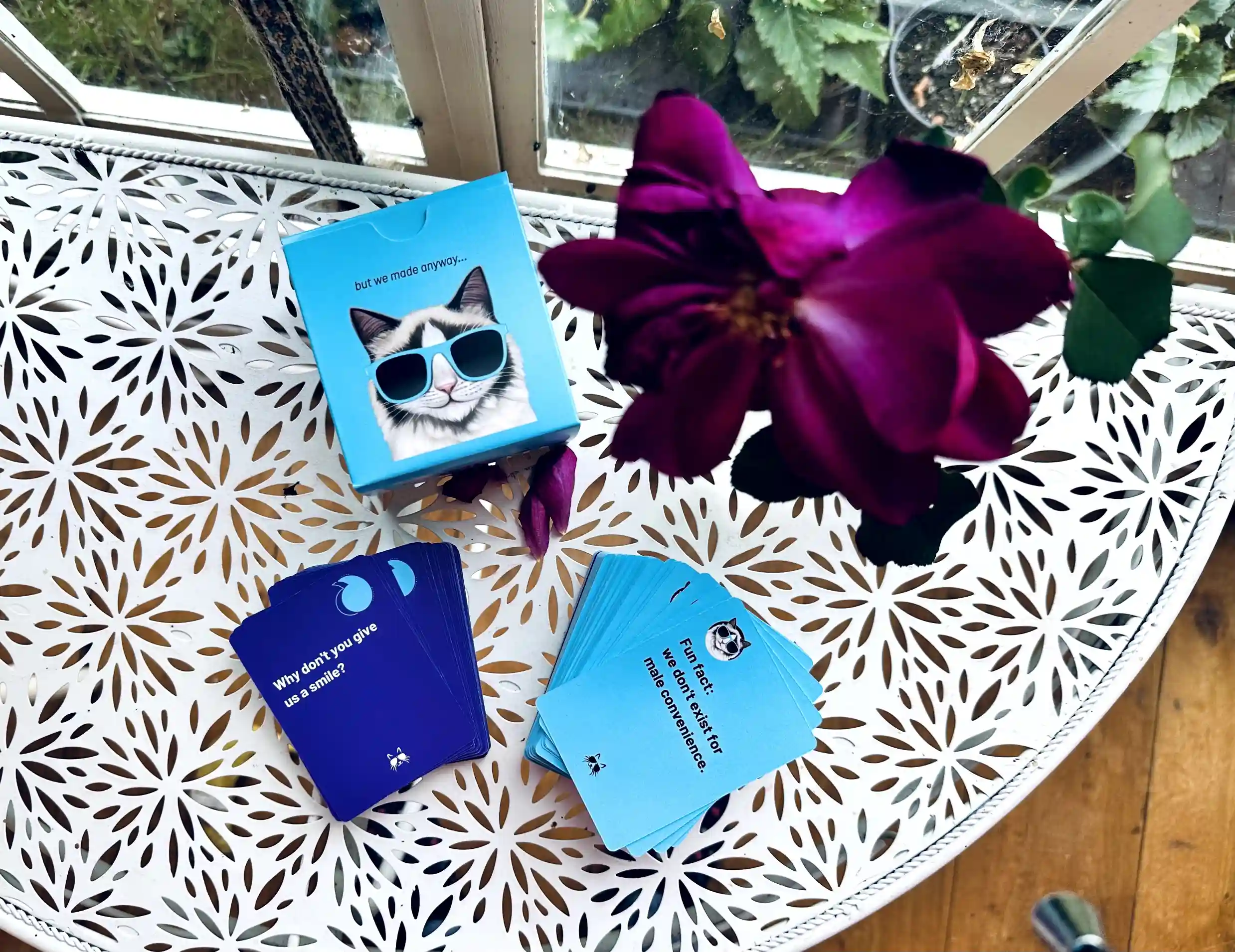 The travel set on a white garden table: the box, a stack of purple Comment cards and a fanned stack of blue Comeback cards